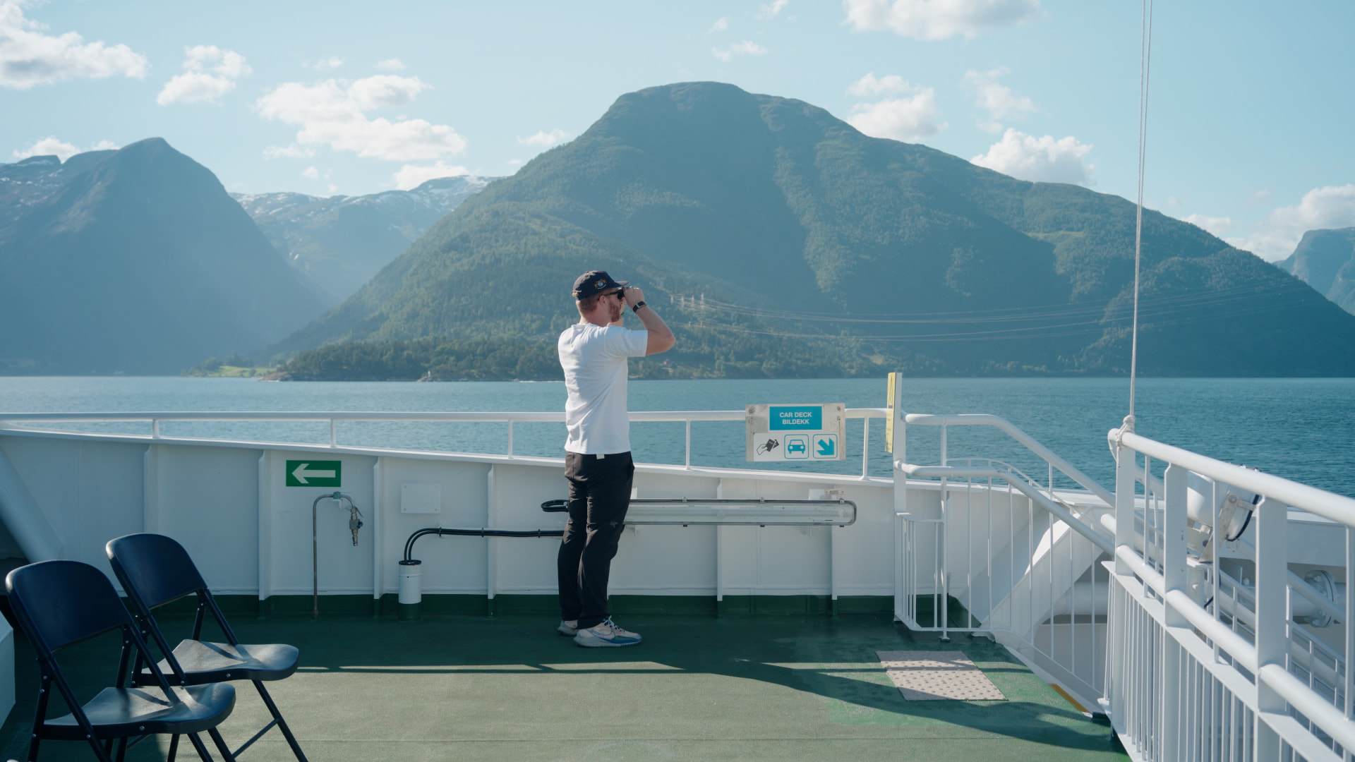 Traveler glassing a fjord from a ferry deck